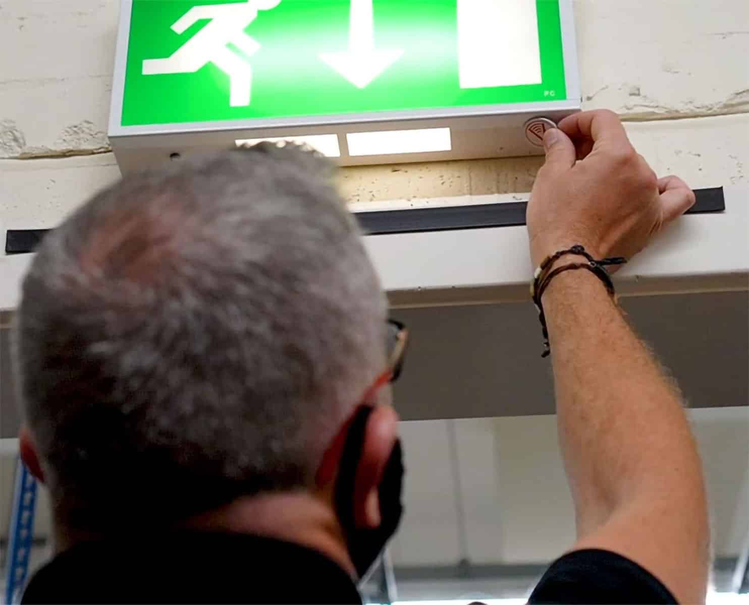Image of a safety inspector in a hard hat reviewing overhead pipes and equipment while pointing upward in an industrial facility.